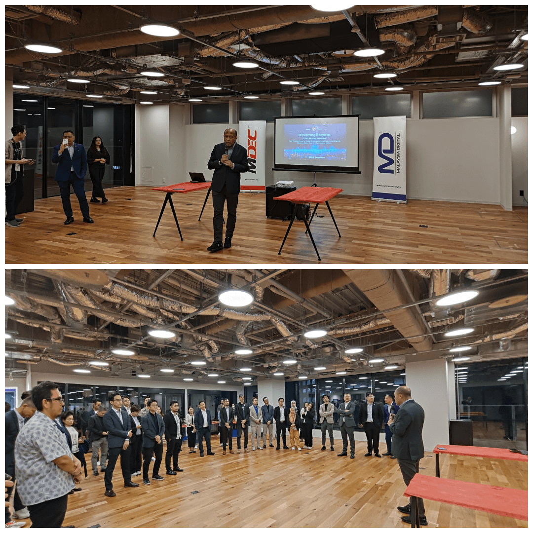 Group of attendees at a digital talent development session held at a co-working space. A speaker is addressing the group, with MDEC branding visible in the background. The setting is a large, modern room with exposed beams and a presentation screen.