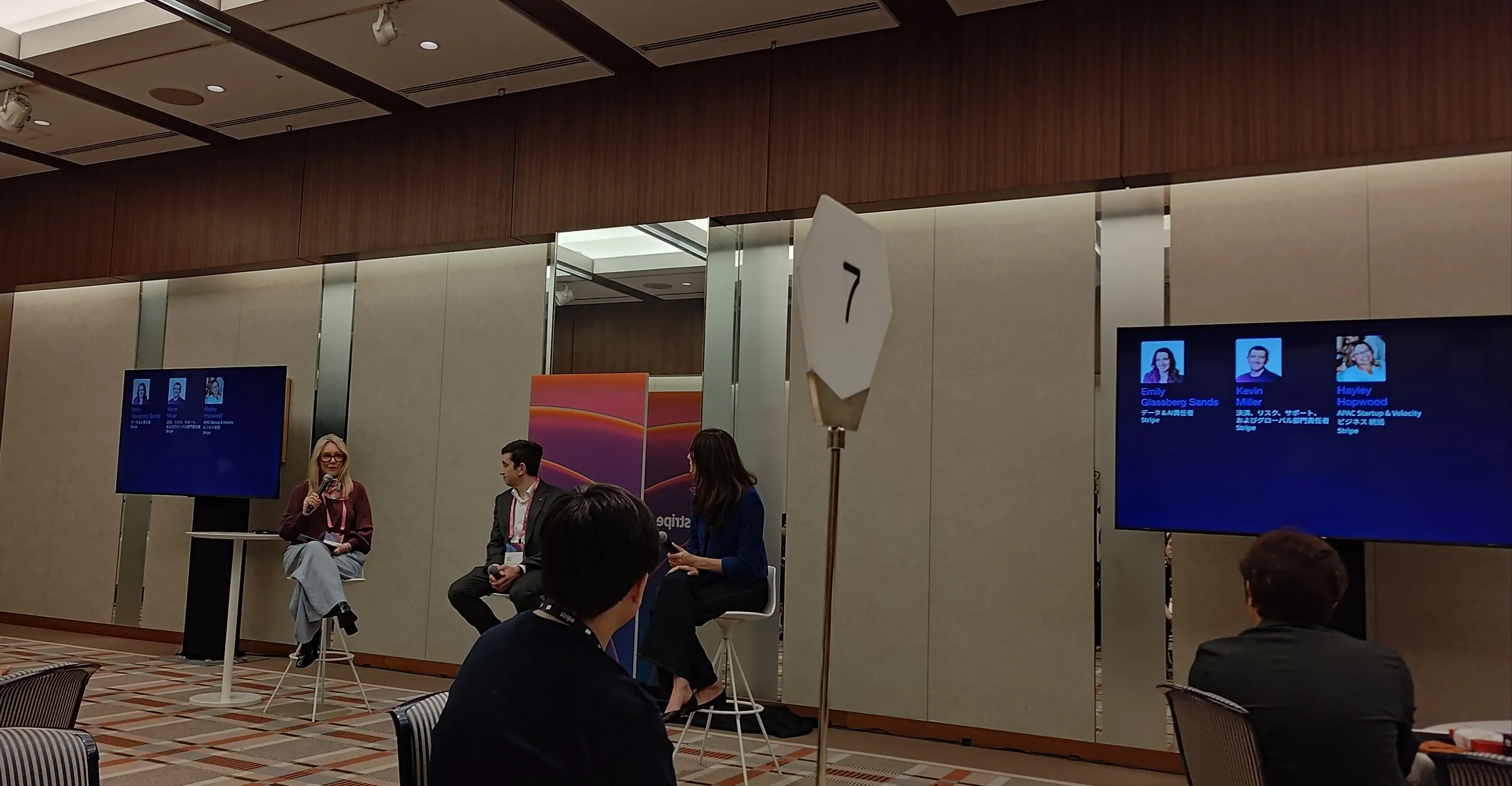 Three people in a panel discussion with a screen showing " conjectures, Gloseberg Sands, Kevin, Hayley Hopwood".