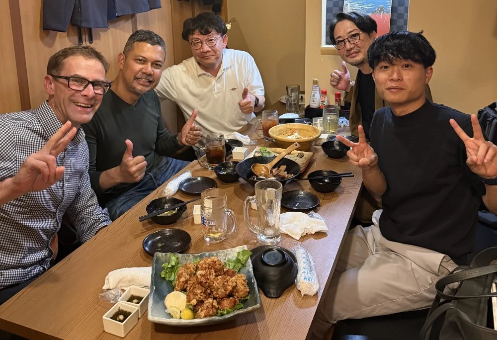 Photo of five men dining together at a table with various Japanese dishes.